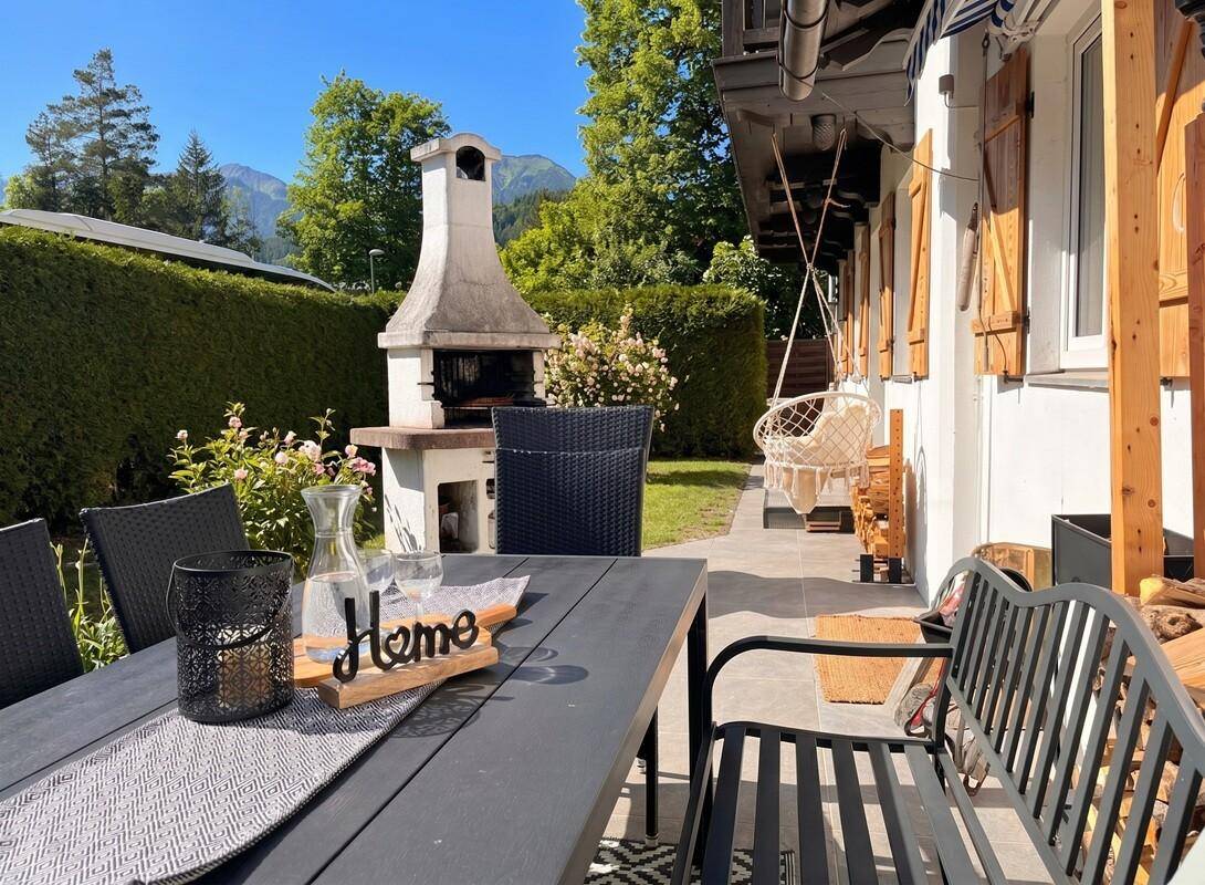 Gemütlicher Essbereich im Freien auf der Terrasse mit Grillkamin und Gartenmöbeln.