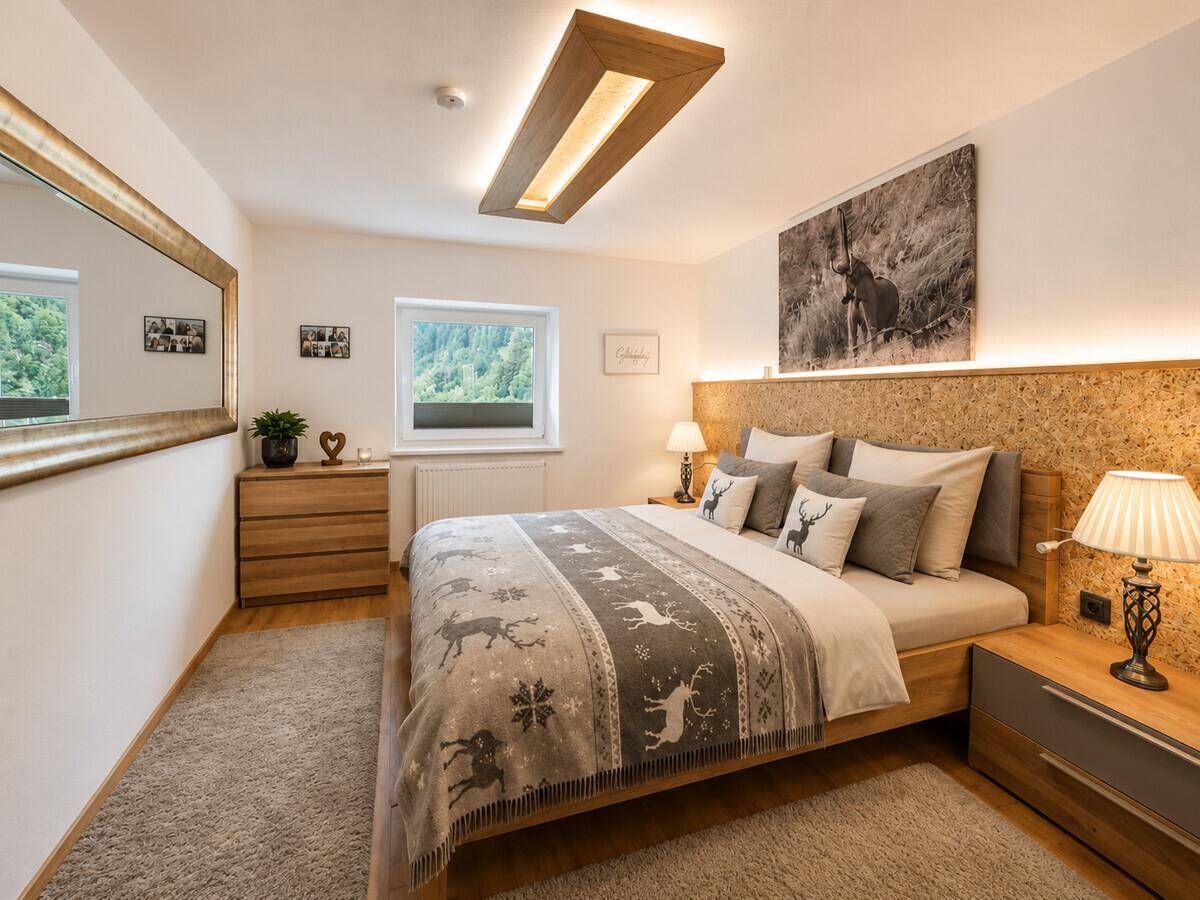 Gemütliches Schlafzimmer mit Holzbett, Teppichboden und indirekter Beleuchtung.
