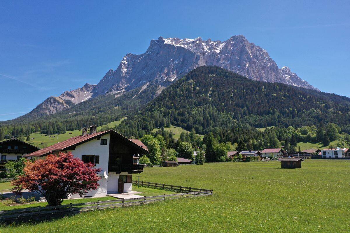 Malerisches Haus in alpiner Landschaft mit weiten Wiesen und beeindruckendem Bergpanorama.