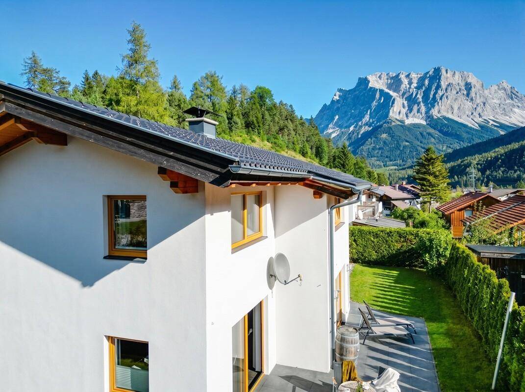 Seitenansicht des Hauses mit Terrasse, Garten und weitem Blick auf die Berge.
