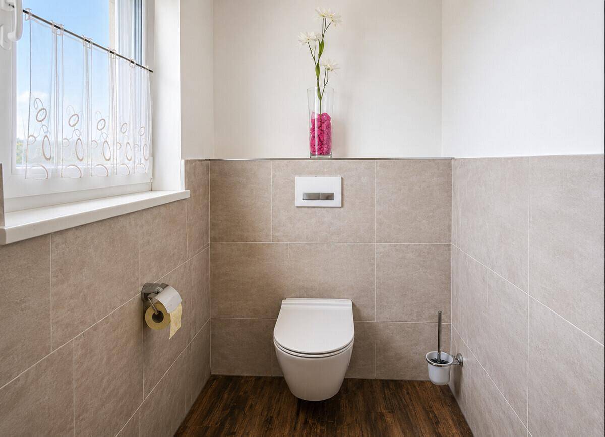 Modernes Gäste-WC mit wandhängendem WC und beigefarbenen Fliesen.
