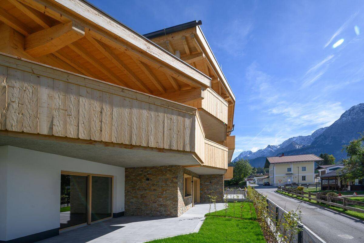 Moderne Architektur mit Holzfassade und Balkonen, eingebettet in die alpine Landschaft.