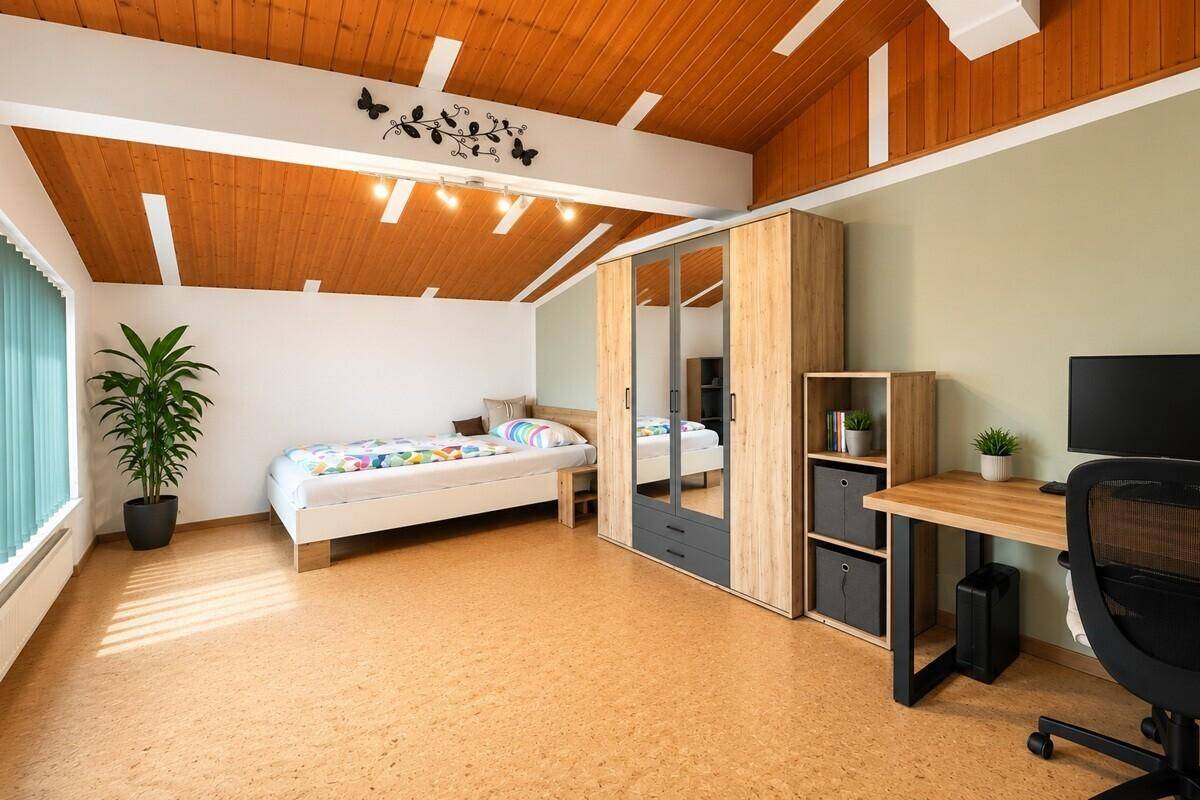 Dachgeschosszimmer mit Holzbalkendecke, Einzelbett und Schreibtisch.