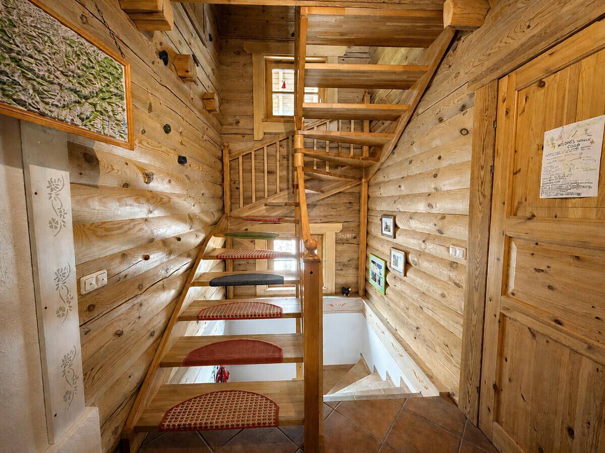 Holztreppe mit Teppichläufern und rustikalen Holzwänden, die die verschiedenen Etagen verbindet.