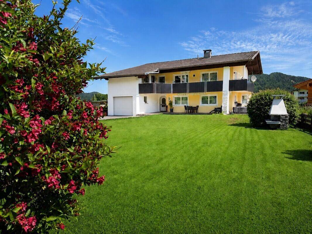 Weitläufiger Gartenbereich mit blühenden Sträuchern und dem Haus im Hintergrund.