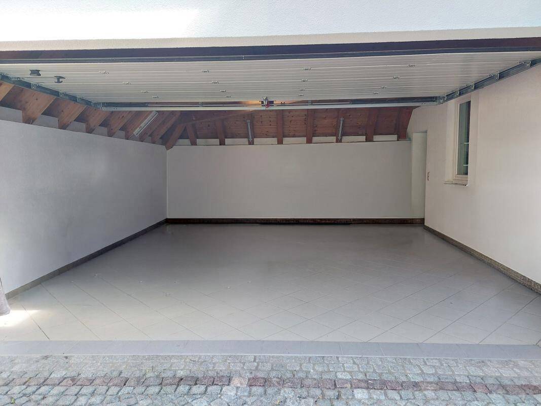 Geräumige Garage mit gefliestem Boden und ausreichend Platz für Fahrzeuge.