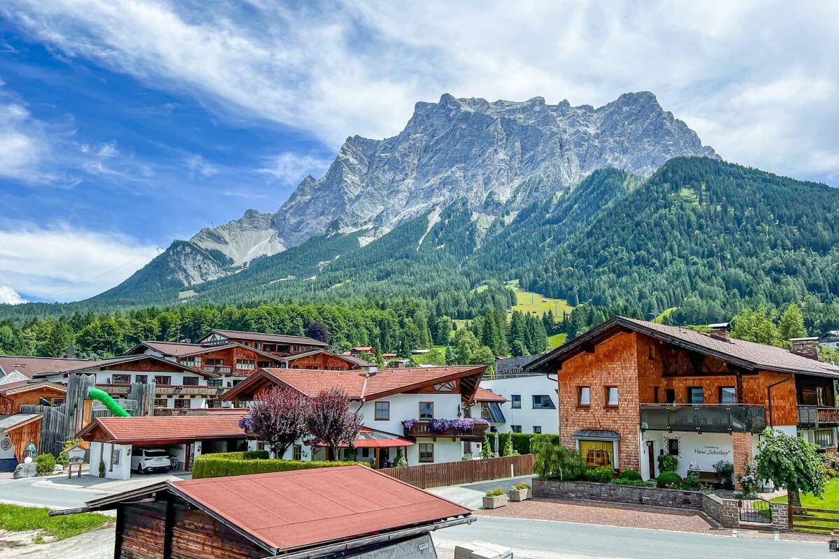 Weitläufiger Ausblick auf die majestätische Bergwelt und ein traditionelles Dorf.