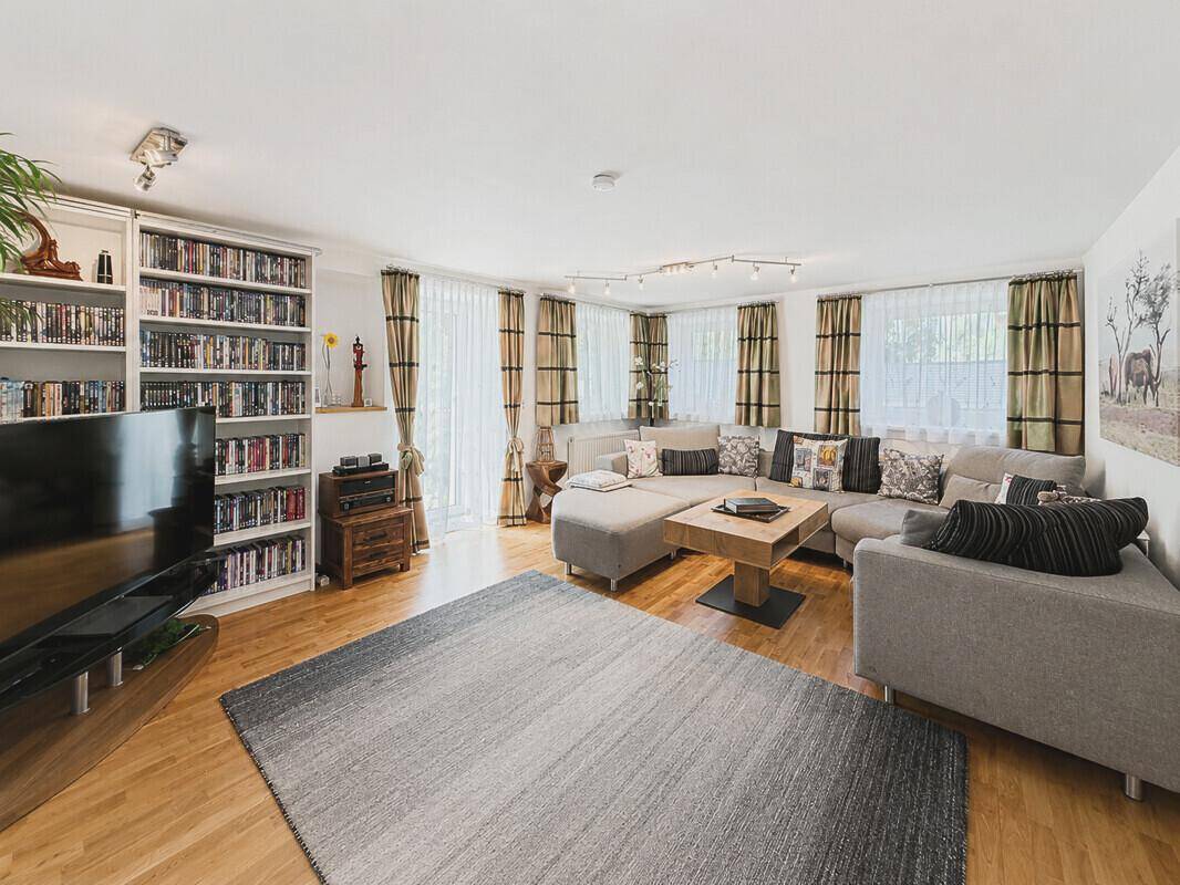 Geräumiges Wohnzimmer mit Holzboden, großem Sofa und Bücherregal.