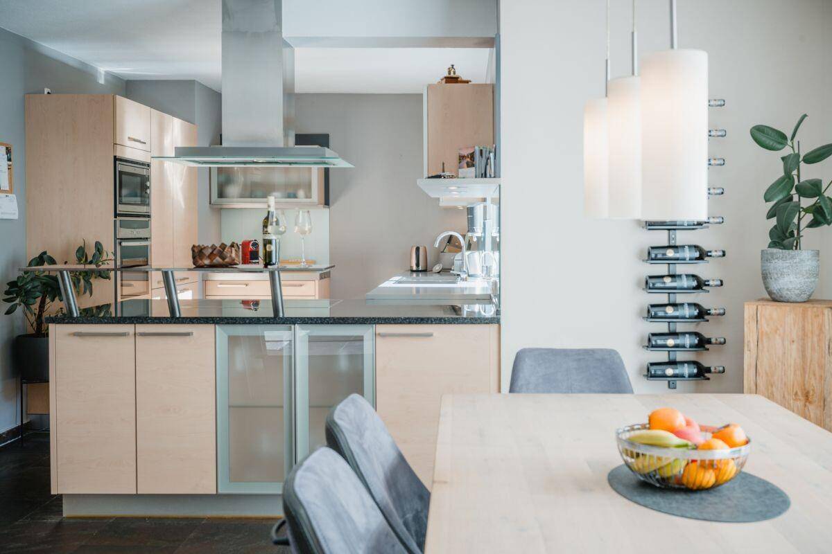 Moderne Einbauküche mit Holzfronten, Kochinsel und Essbereich, ideal für gesellige Runden.