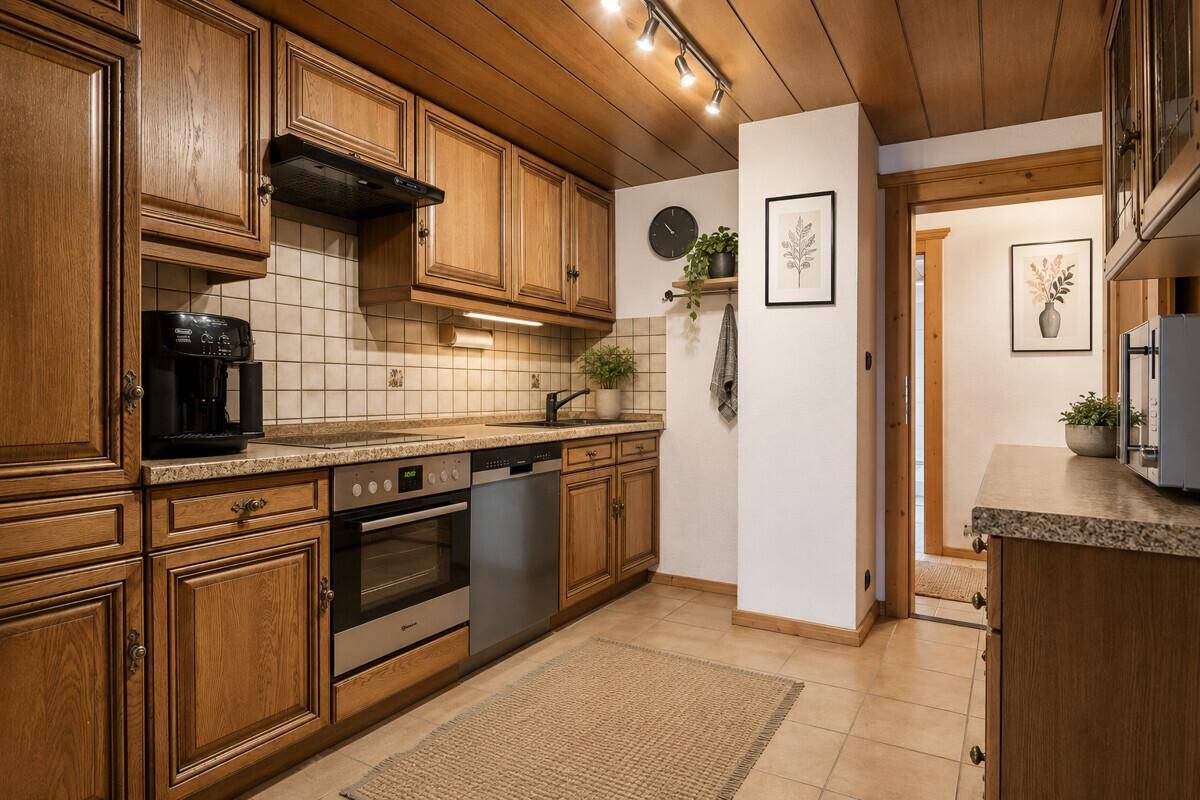 Funktionale Küche mit Holzschränken, Fliesenboden und integrierten Küchengeräten.