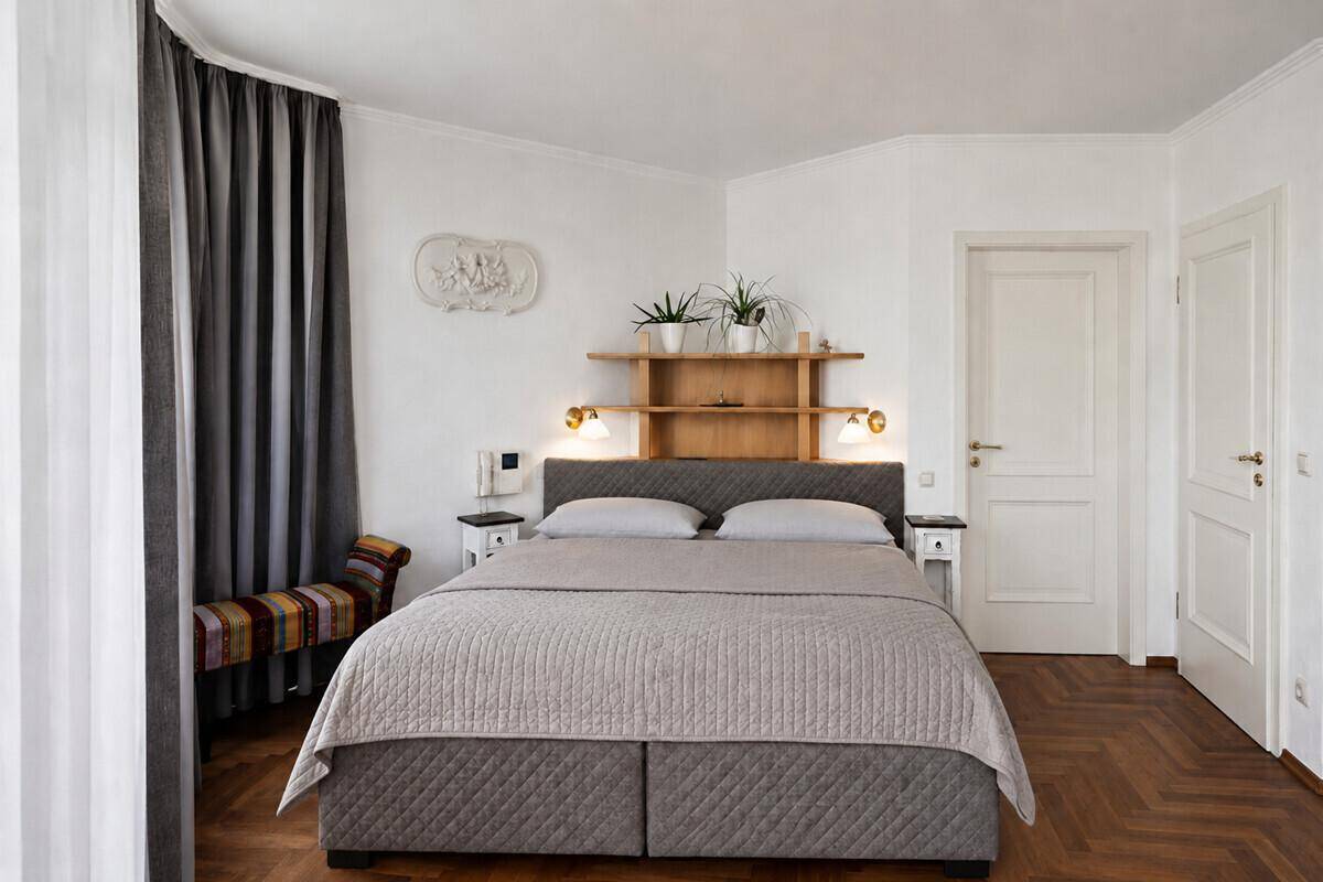 Gemütliches Schlafzimmer mit Doppelbett, Fischgrätparkettboden und schlichter, moderner Dekoration.
