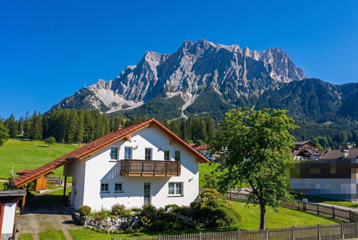 Idyllisches Haus mit Balkon und rotem Dach, eingebettet in eine grüne Berglandschaft.