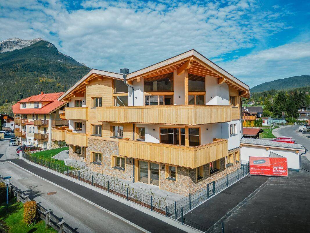Panoramablick auf die moderne Wohnanlage im alpinen Stil mit Holzfassade und Bergblick.
