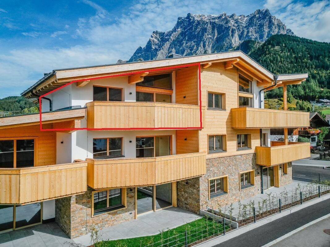 Attraktives Mehrfamilienhaus im alpinen Stil mit großzügigen Balkonen und Blick auf die Berge.