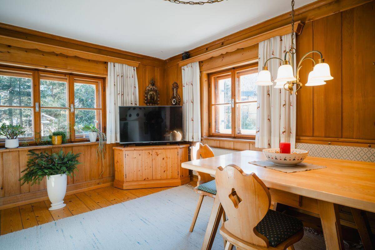 Gemütlicher Essbereich mit Holzvertäfelung, traditionellen Möbeln und Blick ins Grüne.
