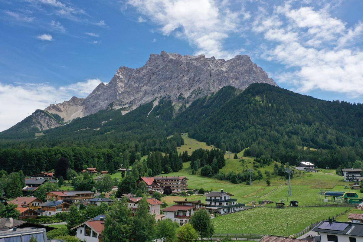 Weitläufiger Blick auf die majestätische Zugspitze und die umliegende grüne Landschaft.