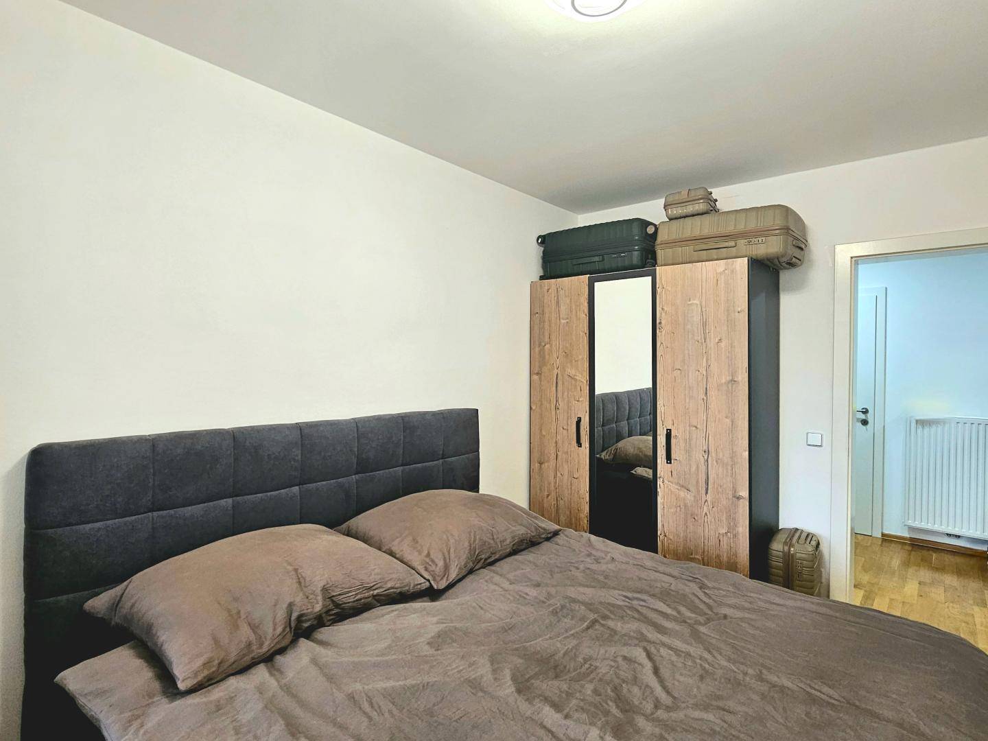 Schlafzimmer mit bequemem Bett und einem modernen Kleiderschrank mit Spiegeltüren.