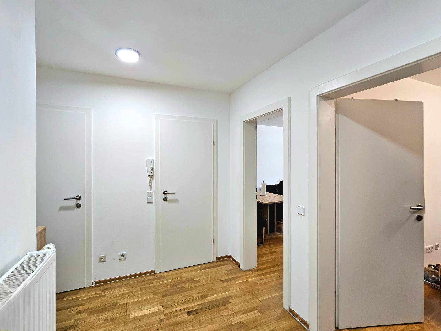 Heller Flur mit Holzboden und mehreren weißen Türen, die zu verschiedenen Räumen führen.