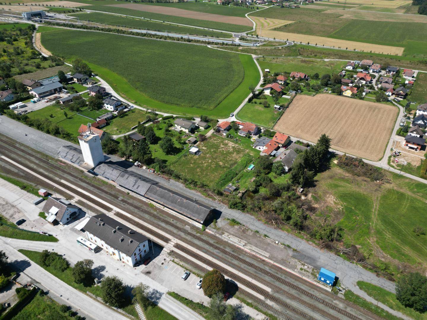 Weitläufige Luftaufnahme des Grundstücks mit Bahnhof, umliegender Bebauung und weiten landwirtschaftlichen Flächen.