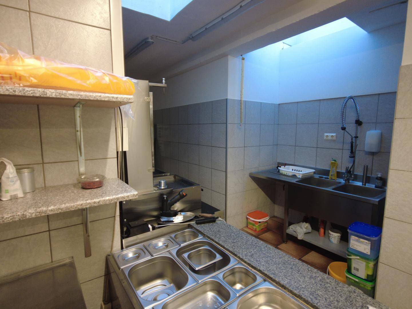Professionelle Küche mit Edelstahlgeräten, doppelter Spüle und gefliesten Wänden für einfache Reinigung.