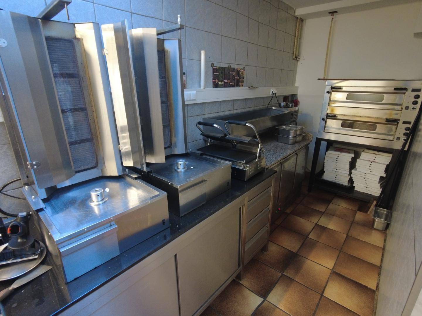 Bereich der professionellen Küche mit Dönergrill, Pizzaofen und weiteren Edelstahlgeräten.