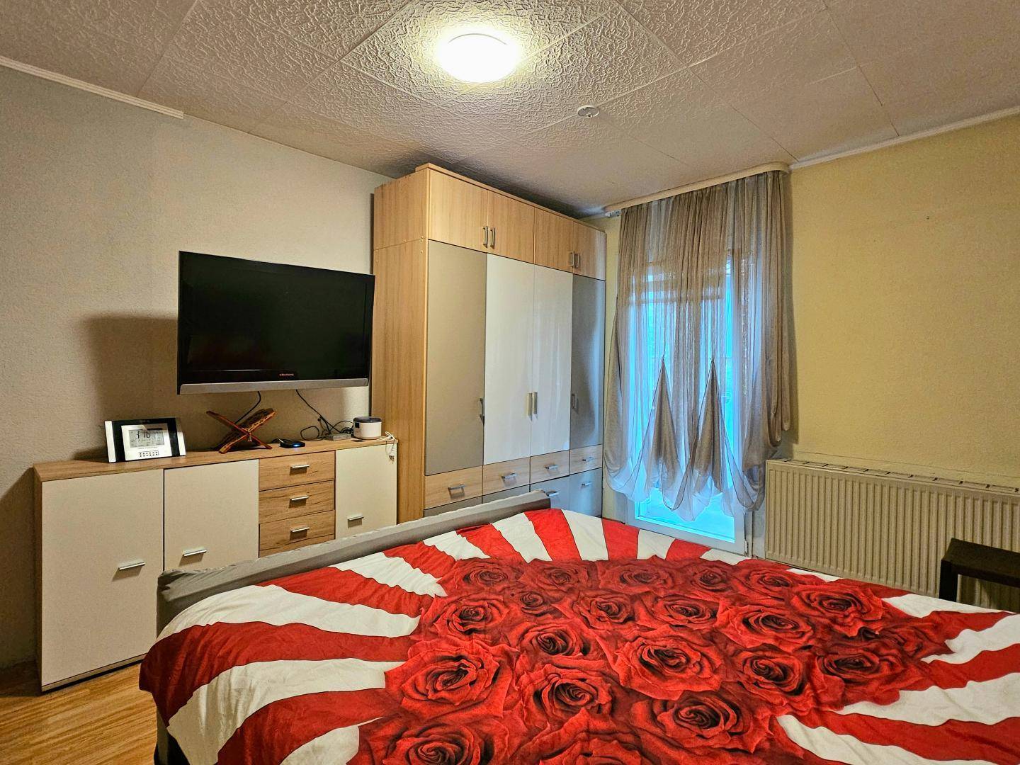 Schlafzimmer mit großem Kleiderschrank, Doppelbett und Fenster für natürliche Belüftung.