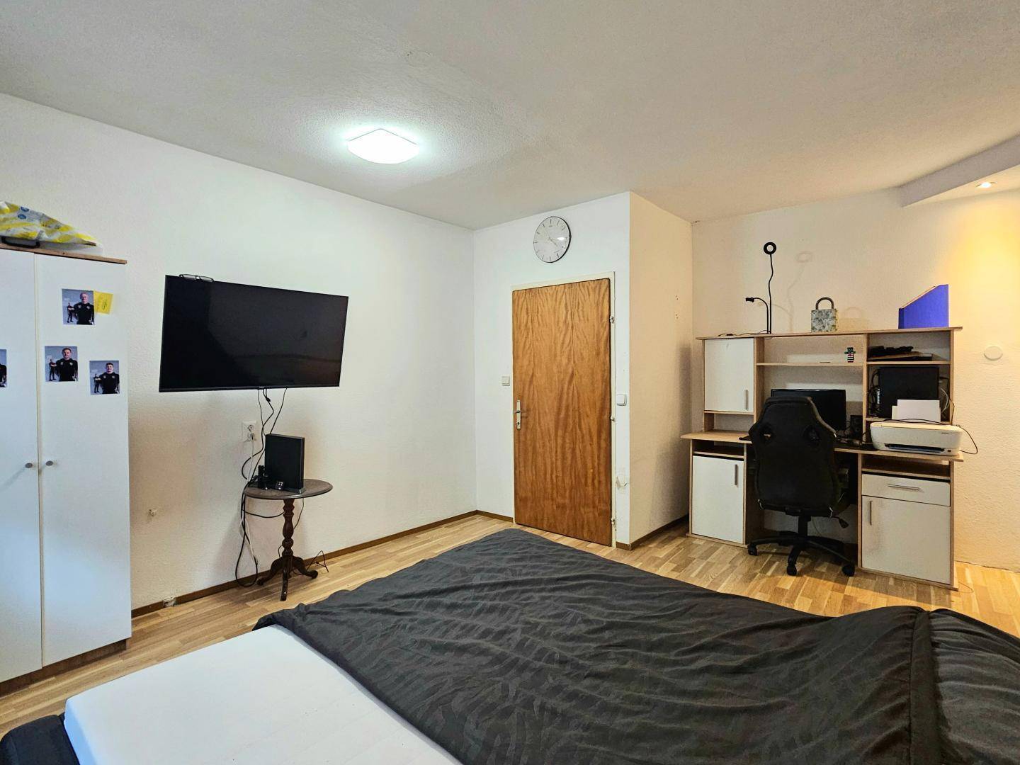 Schlafzimmer mit Doppelbett, Schreibtisch und Fernseher, ideal für Arbeit und Entspannung.