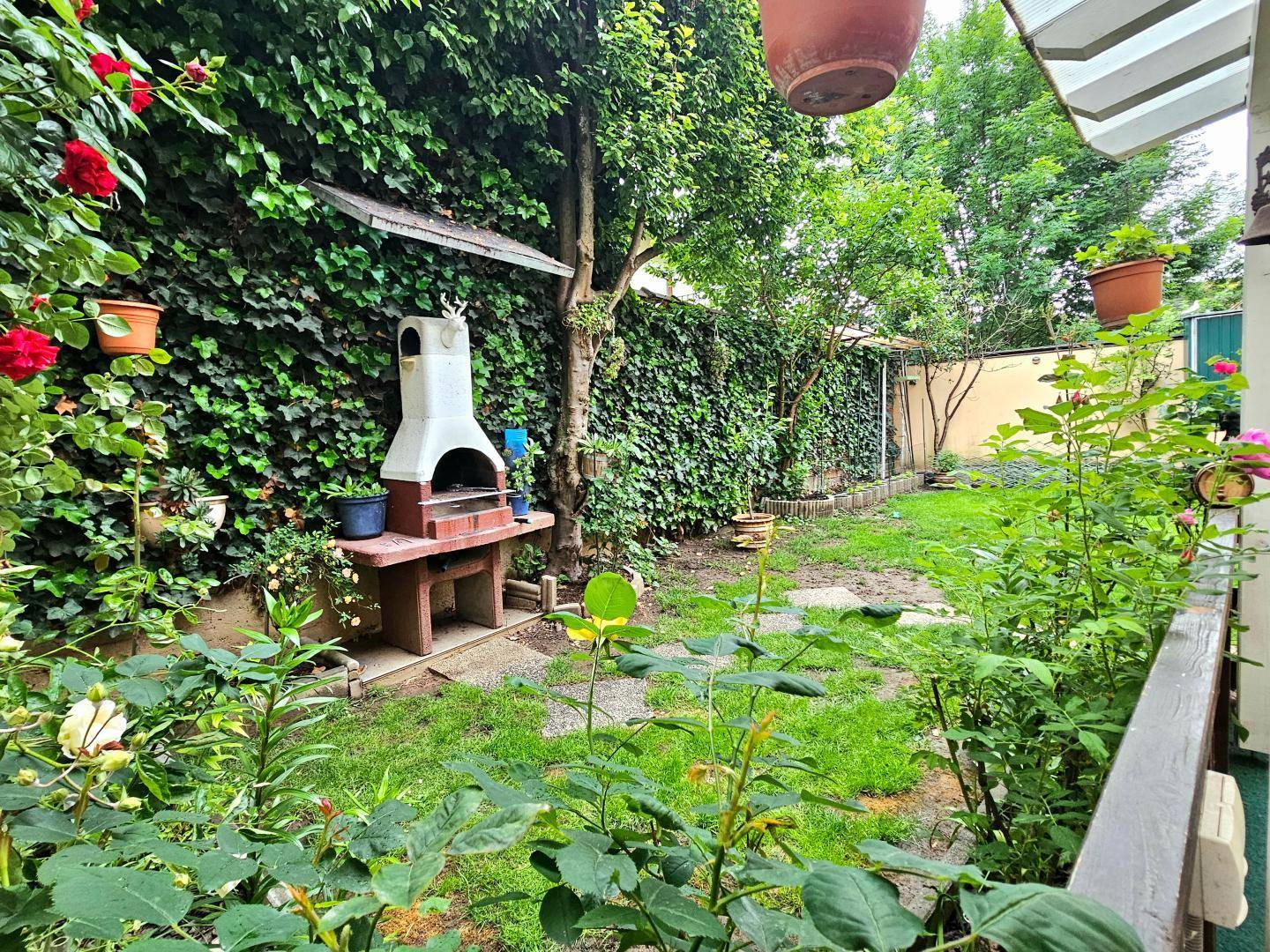 Weitläufiger Garten mit Rasen, Grillplatz und üppiger Bepflanzung für Privatsphäre.
