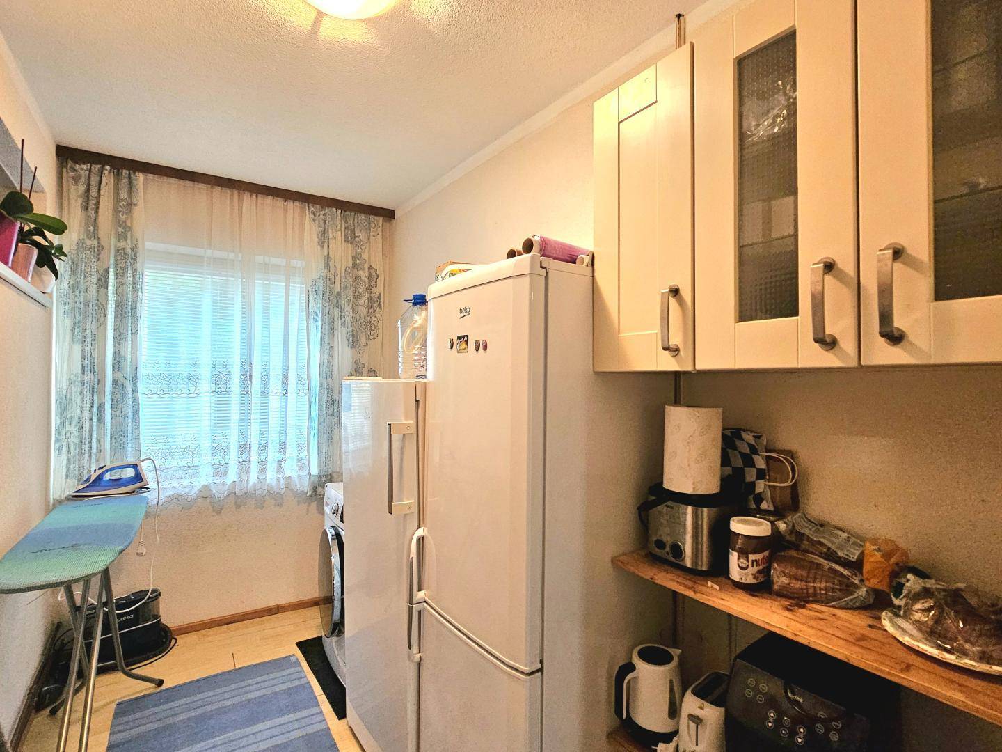 Praktischer Hauswirtschaftsraum mit Waschmaschine, Kühlschrank und Fenster.