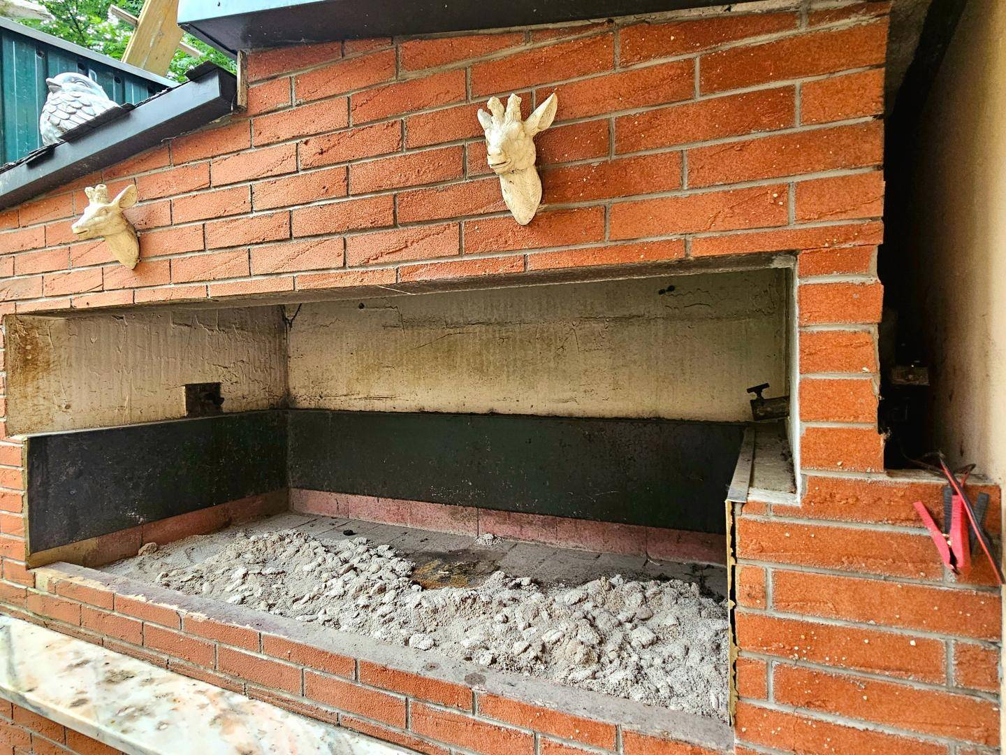 Großer gemauerter Außenkamin oder Pizzaofen mit rustikalen Hirschkopf-Dekorationen.
