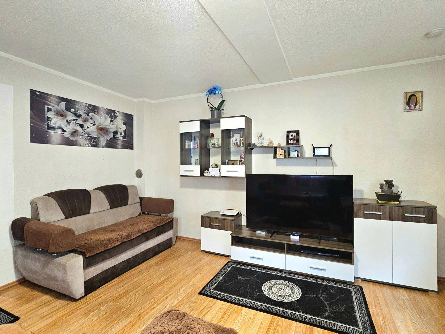 Wohnzimmer mit moderner TV-Wand, Sofa und dekorativen Elementen für eine gemütliche Atmosphäre.