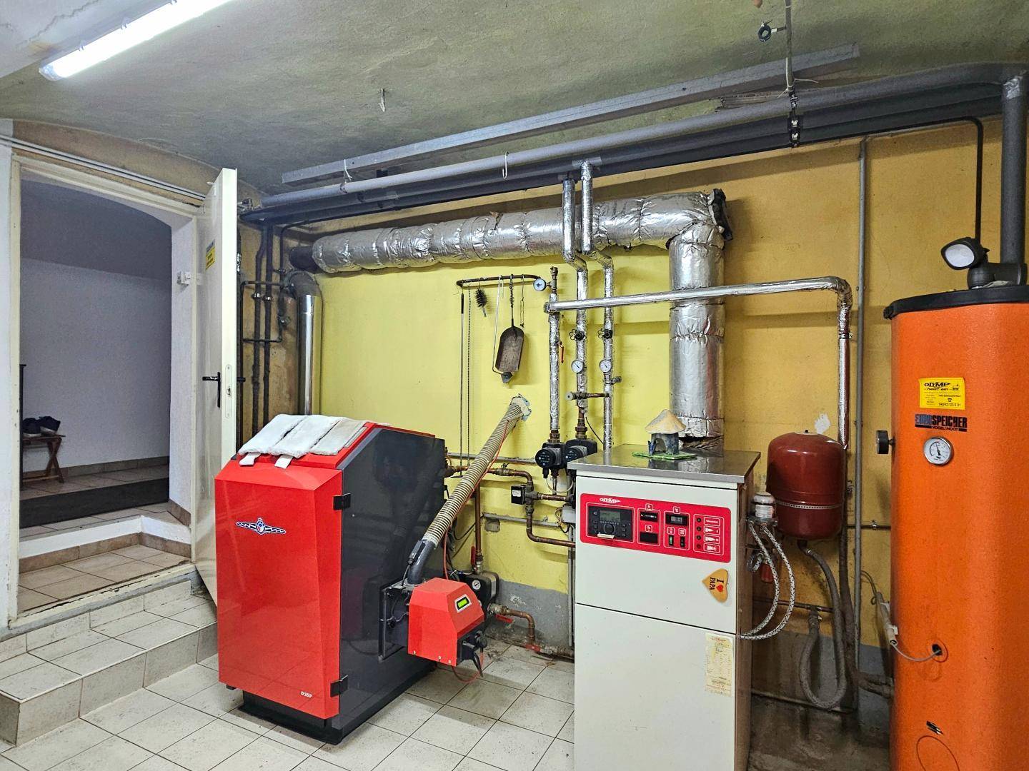 Heizungsraum mit moderner Heizungsanlage und Warmwasserspeicher im Keller.
