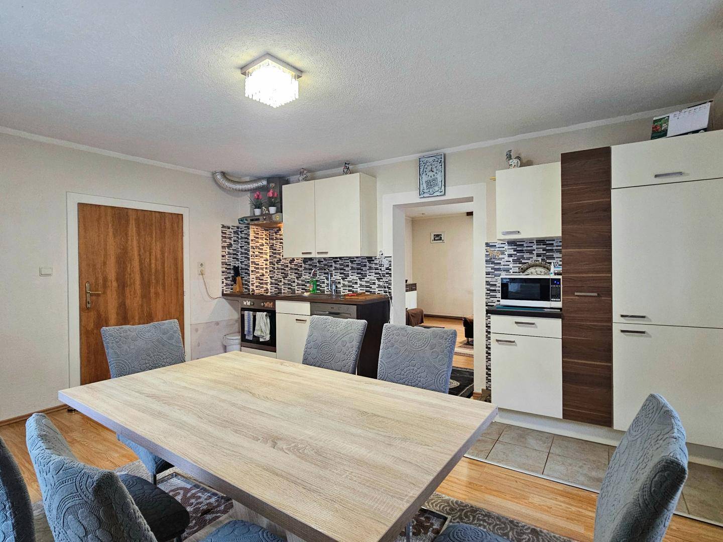 Essbereich mit Holztisch und Stühlen, angrenzend an eine funktionale Küche mit Fliesen.