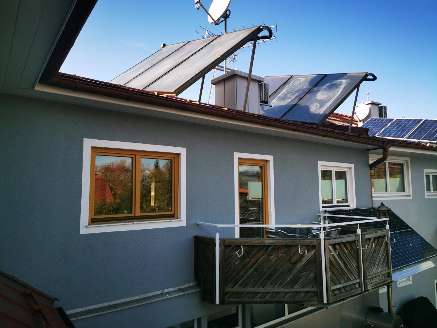 Kleiner Balkon an der Fassade eines Gebäudes mit Solaranlagen auf dem Dach.