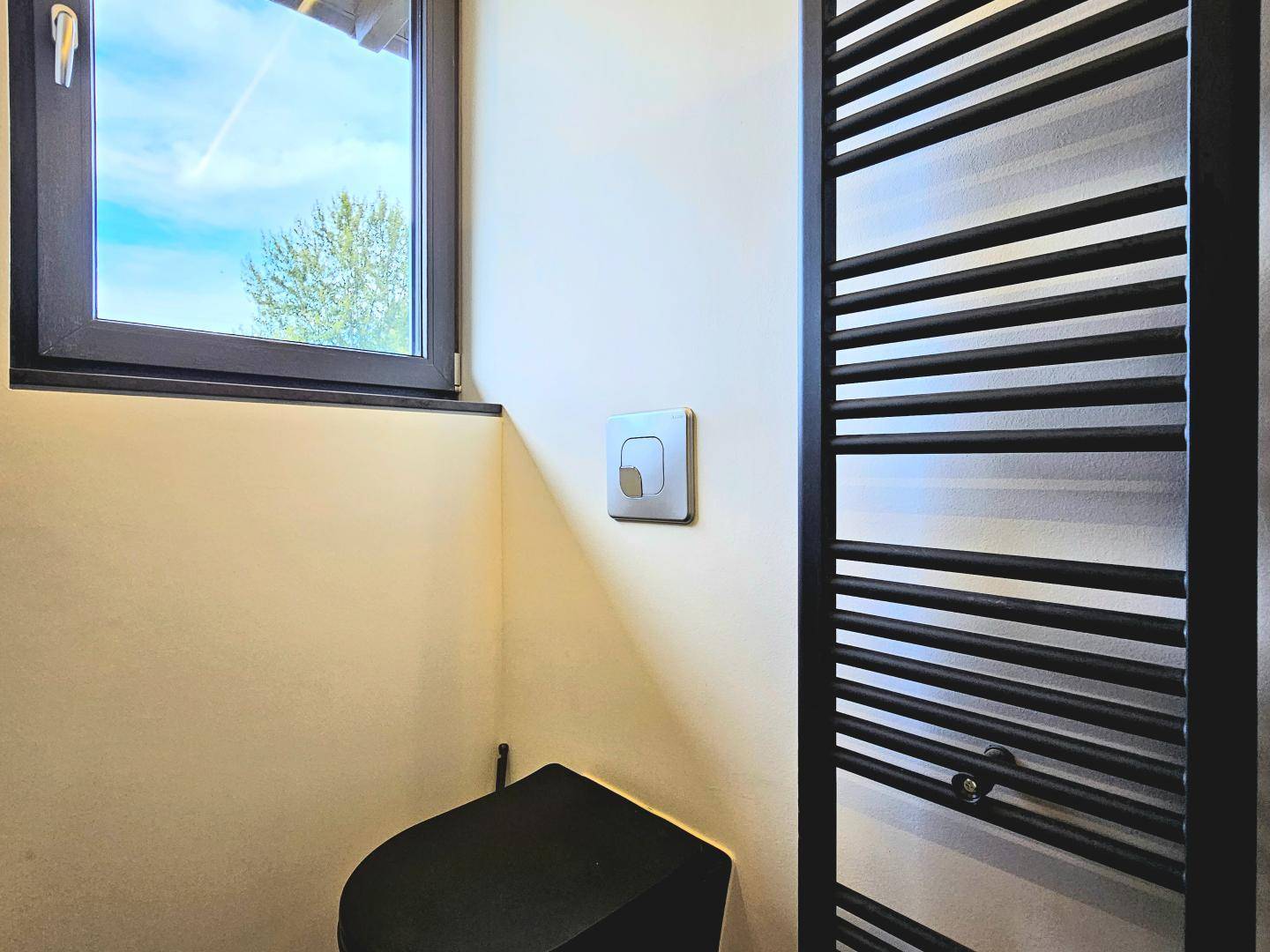 Detailansicht des modernen Badezimmers mit Fenster und schwarzem Heizkörper.