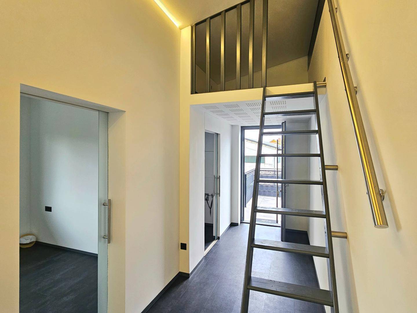 Moderner Eingangsbereich mit Treppe zu einem oberen Bereich und Schiebetür.