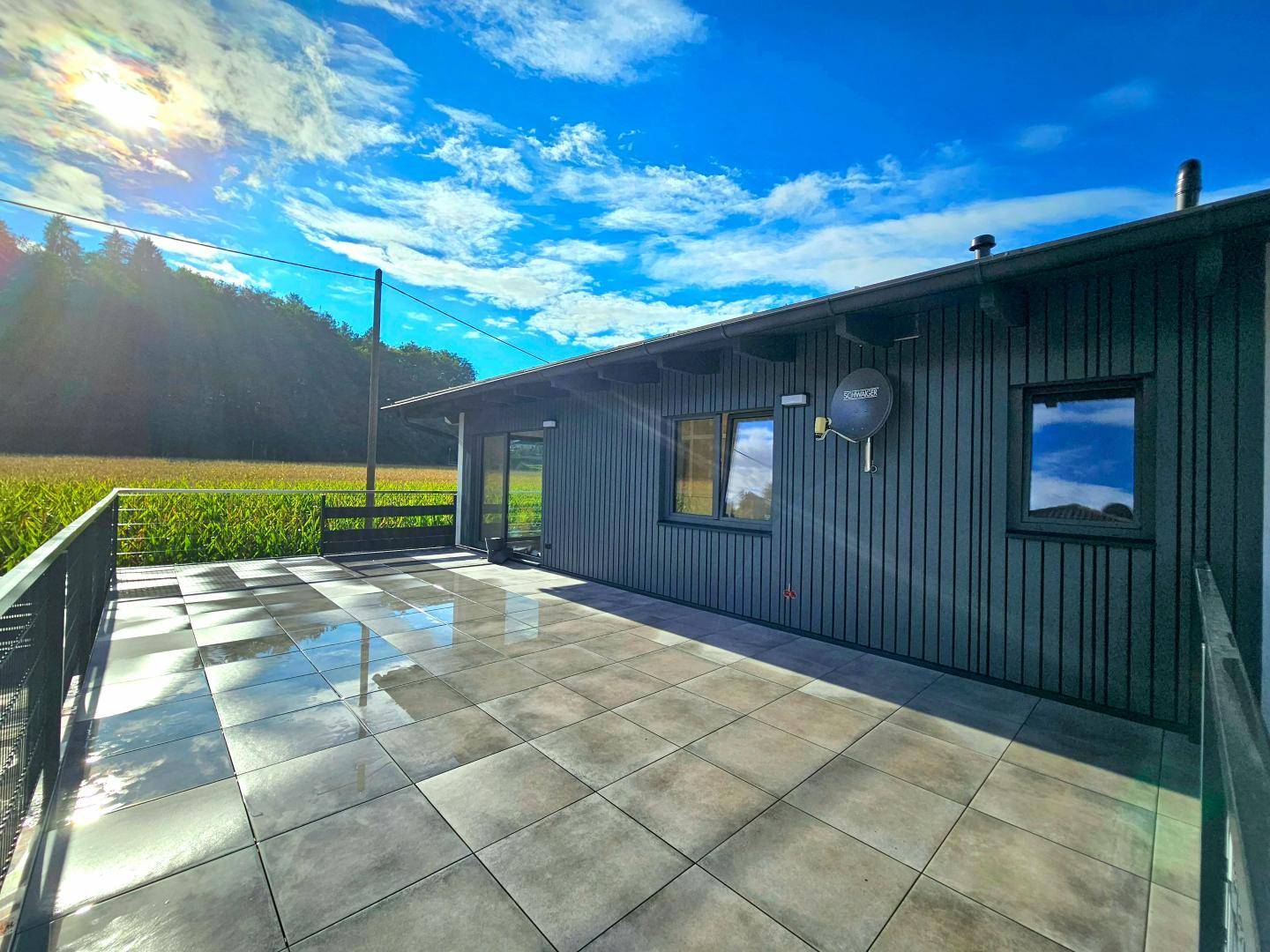 Große geflieste Terrasse mit Blick auf die umliegende Natur und Felder.