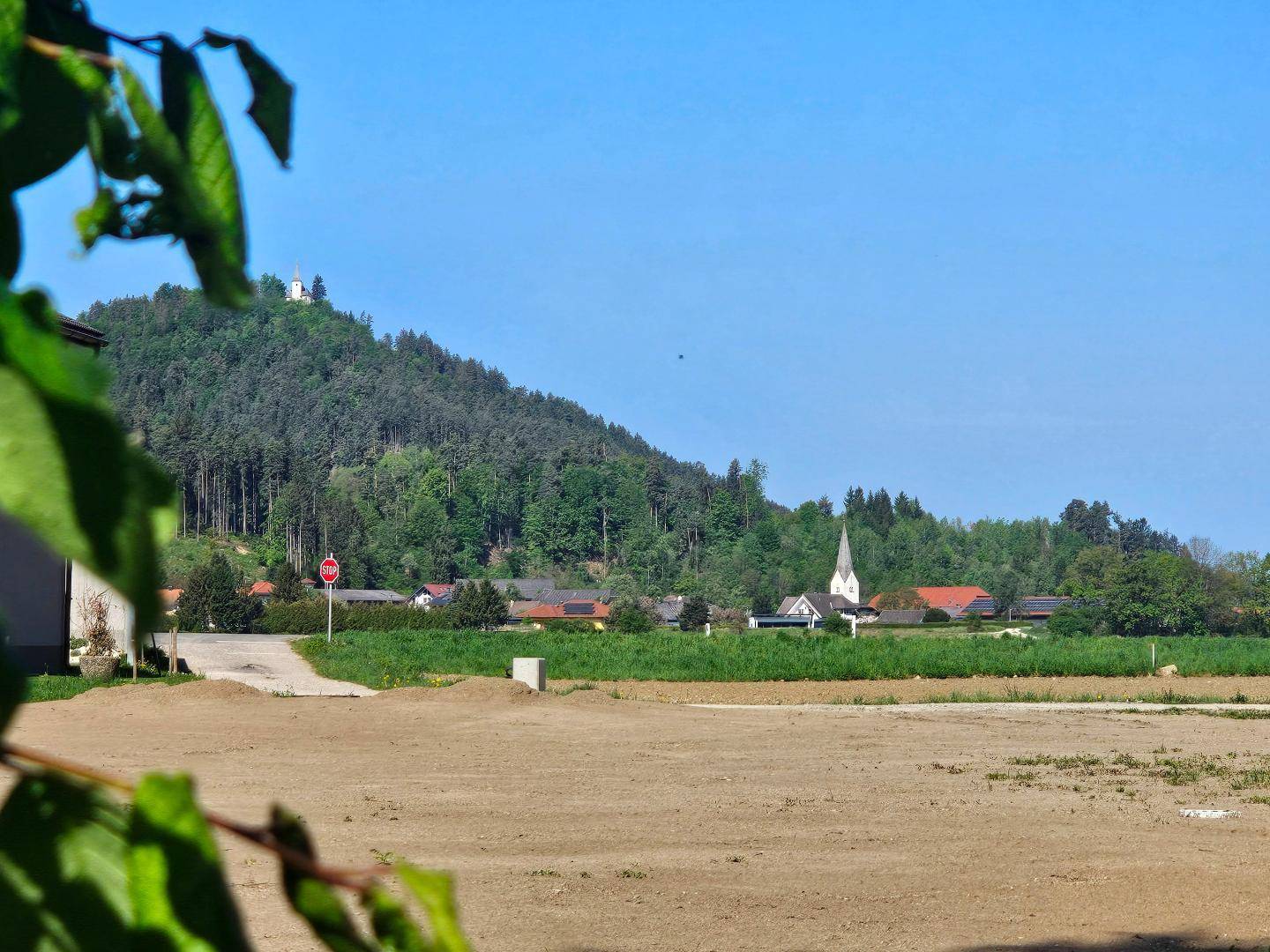 Freigelegtes Grundstück mit Blick auf ein charmantes Dorf und bewaldete Hügel in der Ferne.