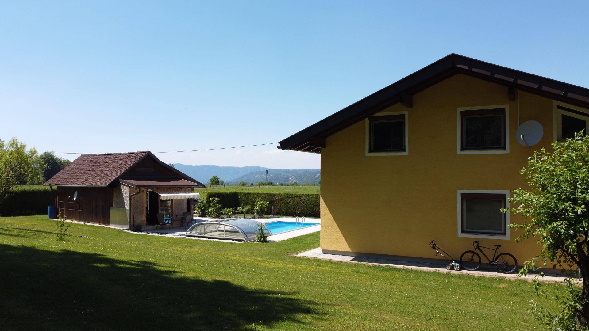 Ansicht des Hauses und des Nebengebäudes mit Pool, umgeben von Hecken und weitem Blick.