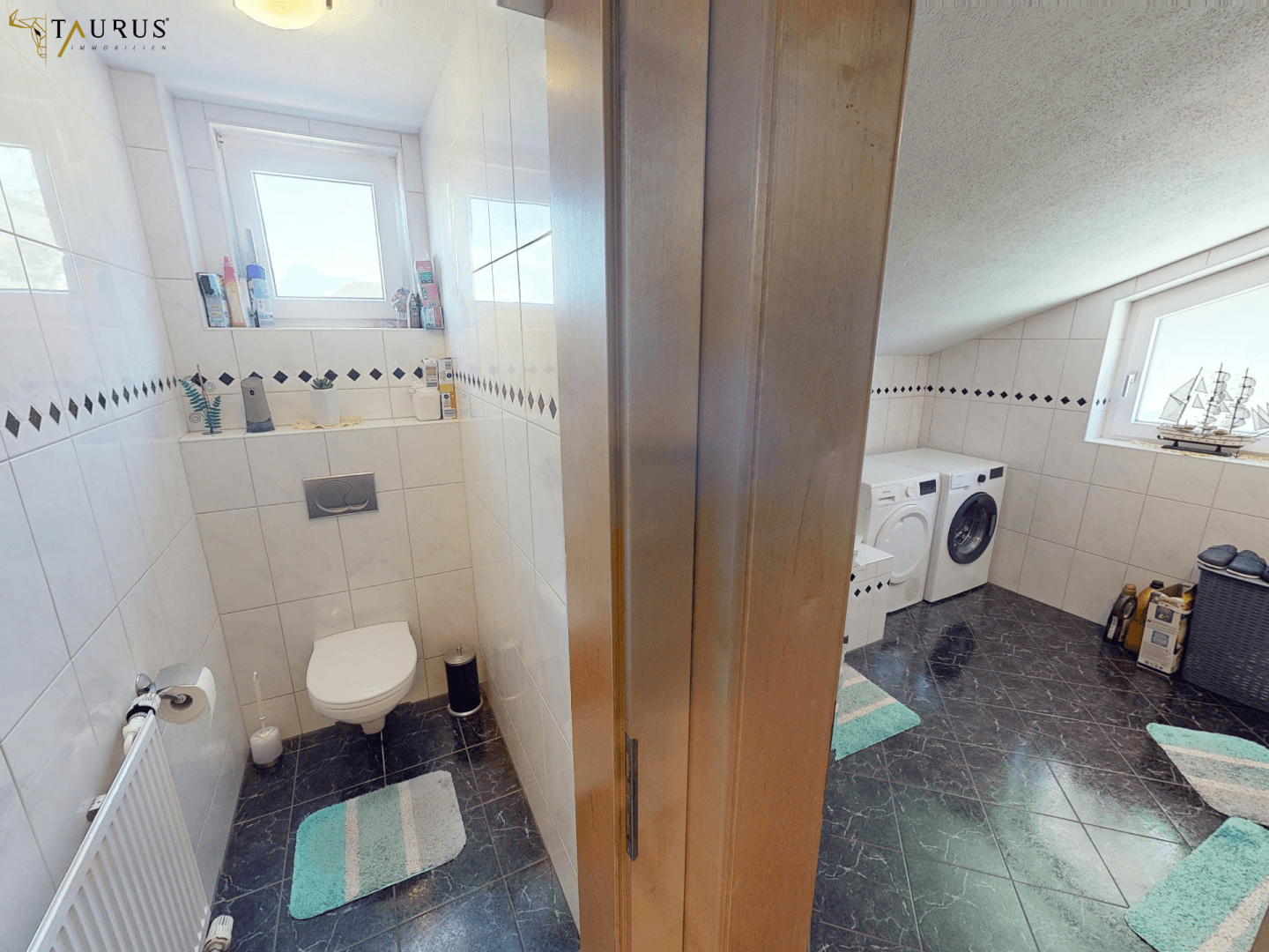 Badezimmer mit WC, Fenster und weißen Fliesen mit dekorativer schwarzer Bordüre.