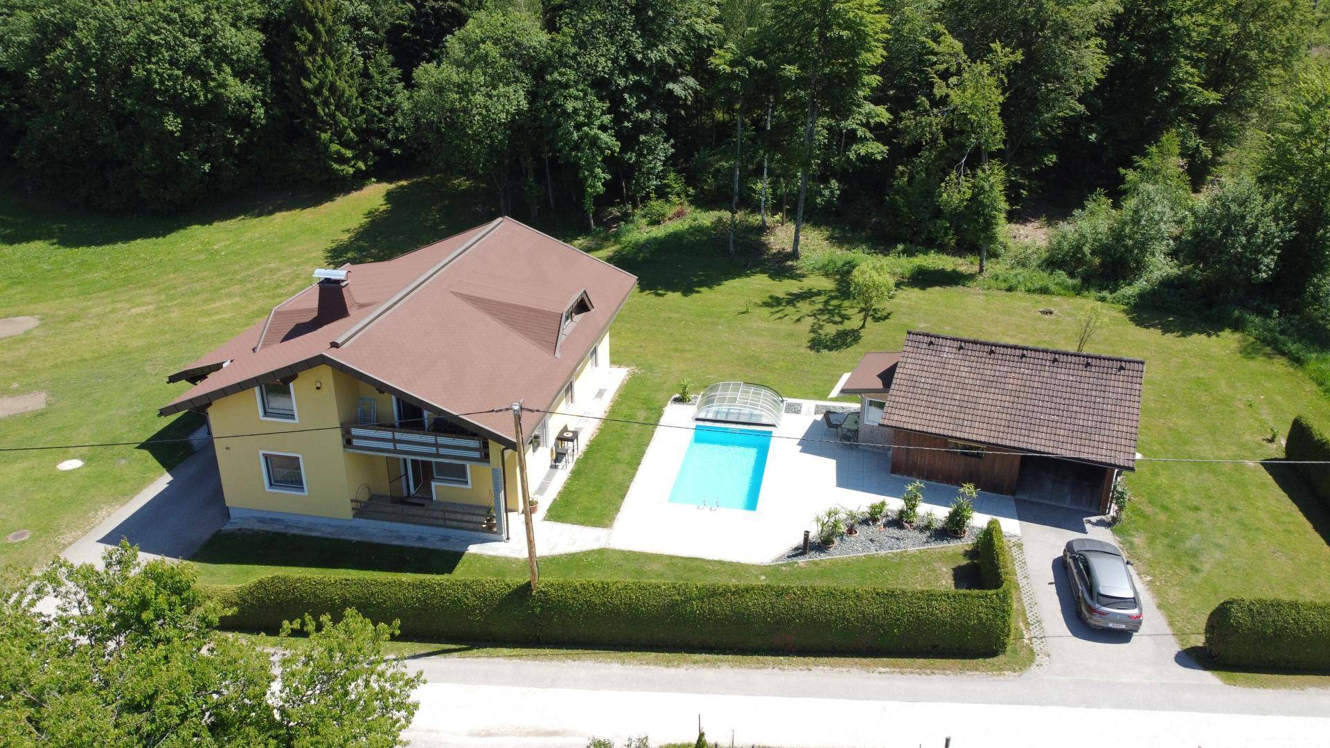Luftaufnahme des Anwesens mit Haupthaus, Nebengebäude, Pool und weitläufigem Gartenbereich.