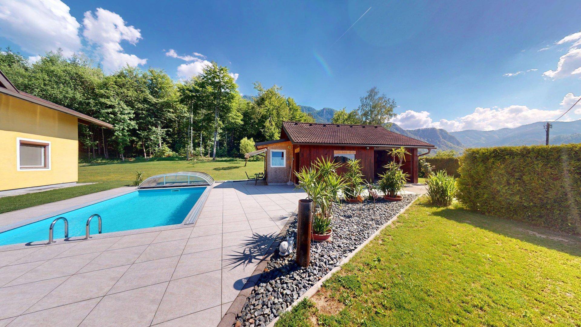 Außenbereich mit Pool, gepflasterter Terrasse und einem charmanten Holz-Nebengebäude.