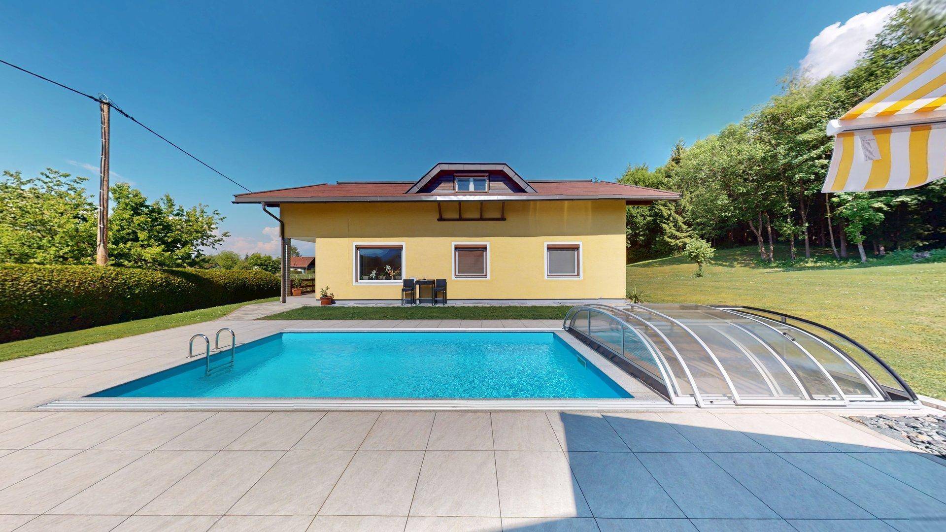 Das Haus mit Pool und überdachter Terrasse, umgeben von einem weitläufigen Garten.