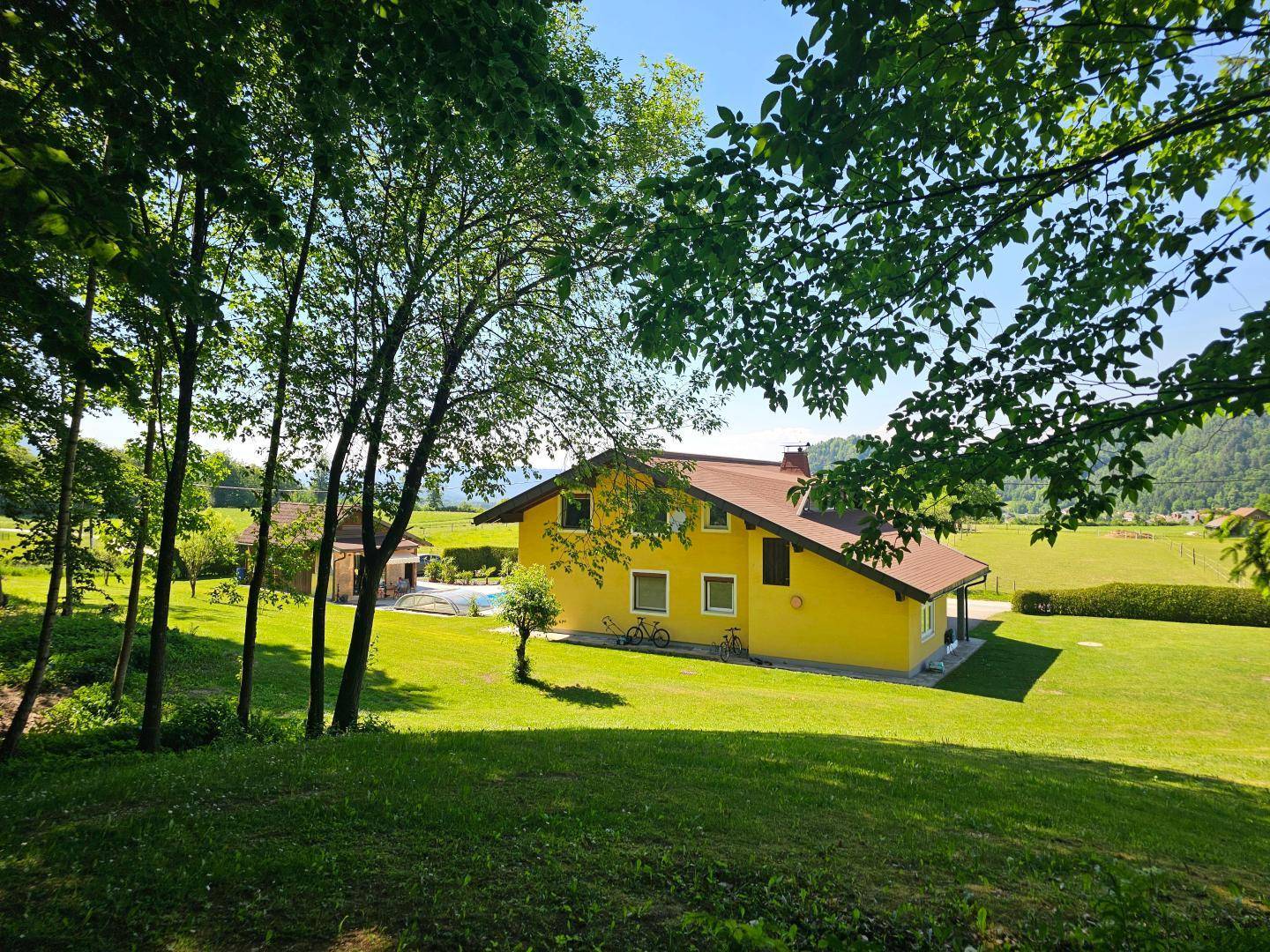 Das gelbe Haus ist von hohen Bäumen umgeben und bietet einen idyllischen Blick auf die Landschaft.