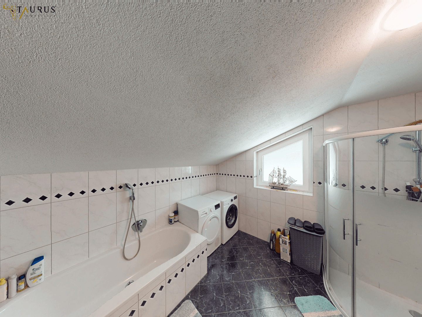 Badezimmer mit Badewanne, Duschkabine, Waschmaschine und Dachschräge.