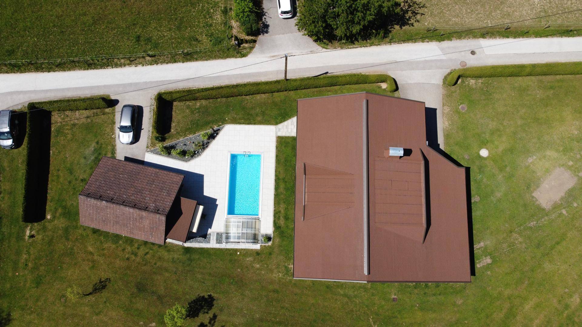 Draufsicht des Grundstücks mit Haus, Nebengebäude, Pool und angrenzender Straße.