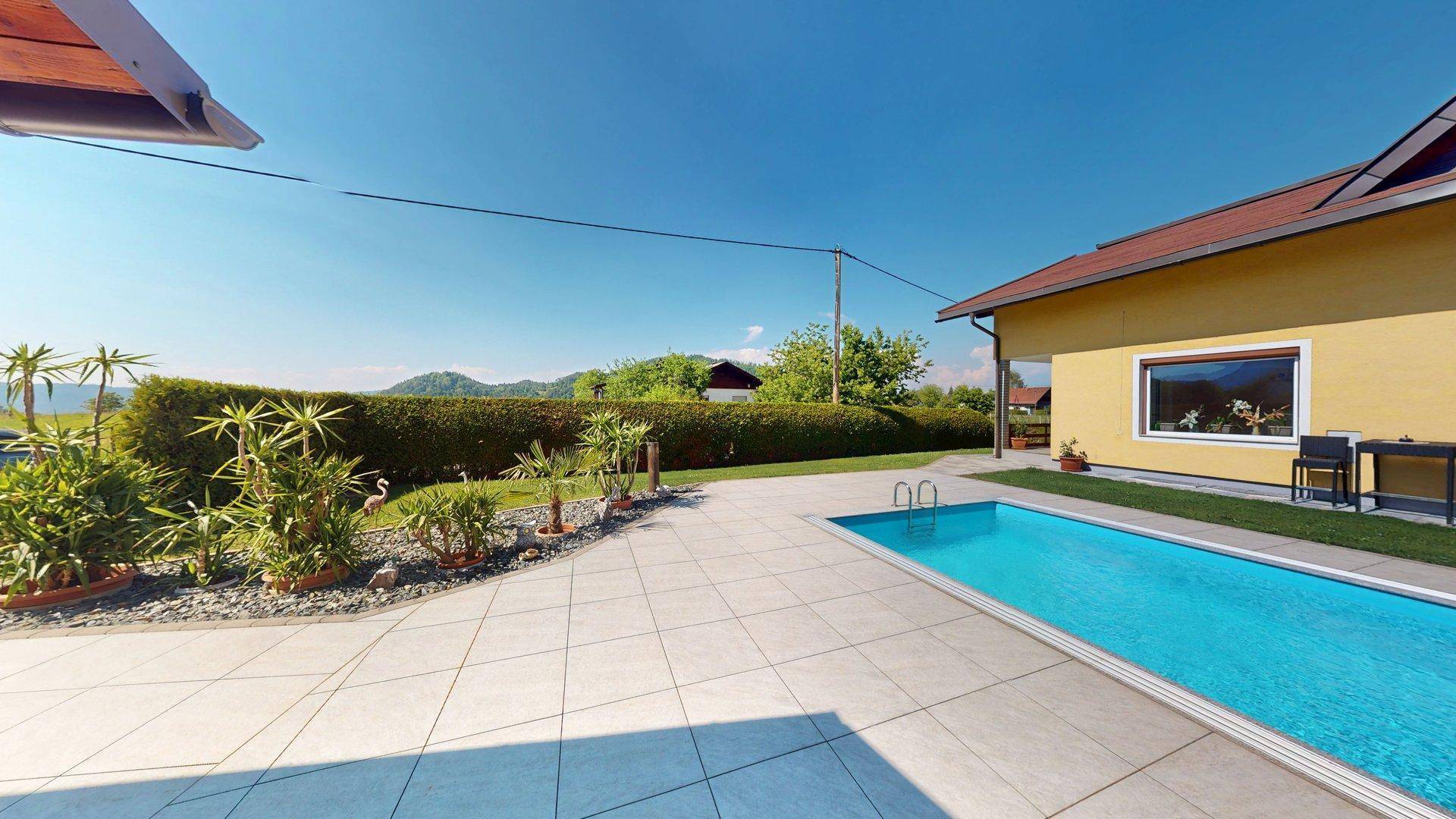 Sonniger Poolbereich mit großzügiger Terrasse und Blick auf die umliegende Landschaft.