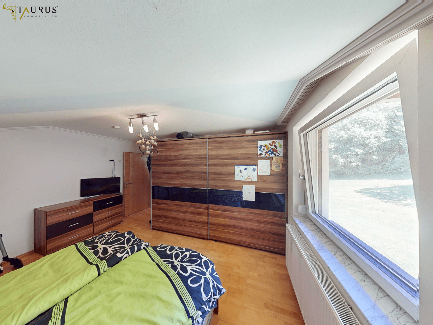 Schlafzimmer mit großem Holzschrank, Doppelbett und Blick ins Grüne.