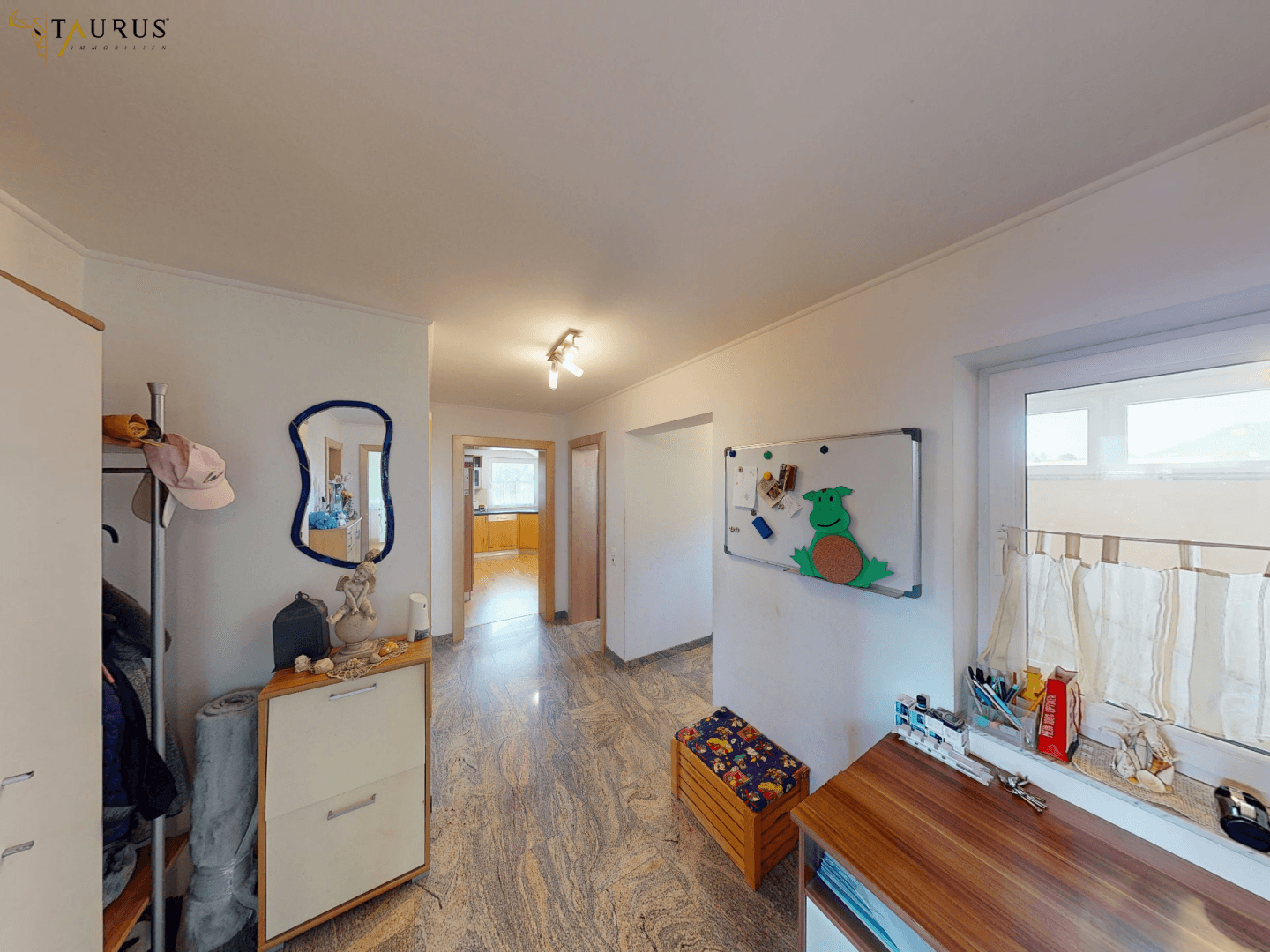 Eingangsbereich mit Marmorfliesenboden, Schuhschrank und Spiegel.