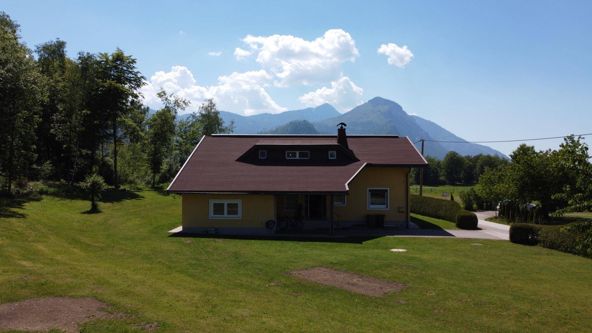 Das Haus eingebettet in eine grüne Landschaft mit beeindruckendem Bergblick im Hintergrund.